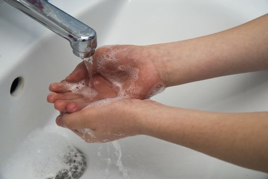 Kid washing hands in bathroom, coronavirus pandemic prevention