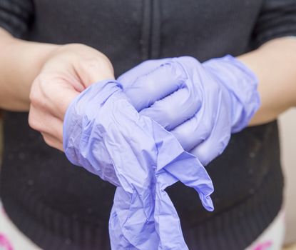 Woman pulling surgical gloves on hands