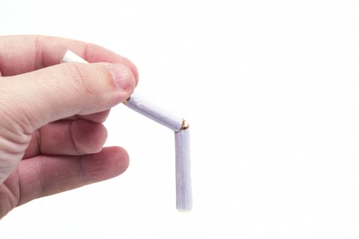 Hand holding a broken cigarette over a white background, no smoking campaign