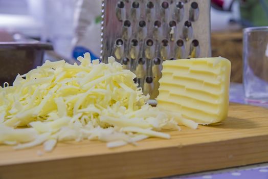 Grated hard cheese on wooden cutting board