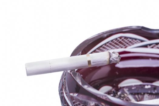 Close up image of cigarette in ashtray against white