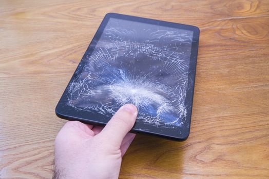 Hand holds a tablet with broken touchscreen, hard damaged display
