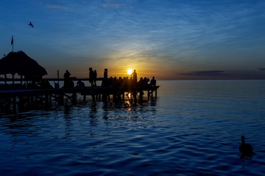 people on a jetty at sunset