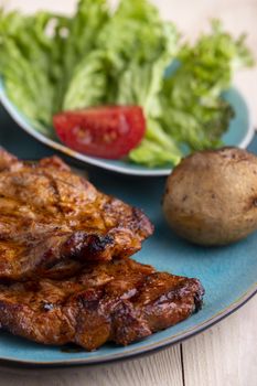 grilled pork steaks on a blue plate