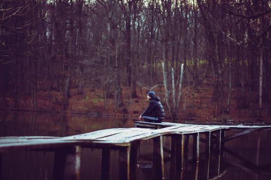 The guy is sitting by the lake