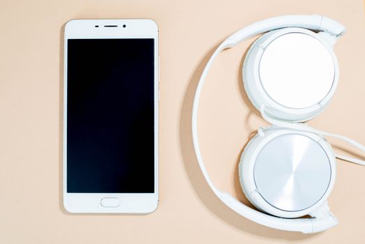 Smartphone and headphones on a pink background