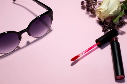Sunglasses and cosmetics on a pink background