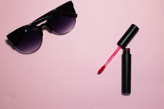 Sunglasses and cosmetics on a pink background