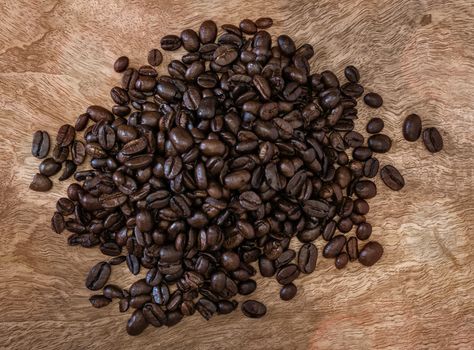 Group of roasted coffee beans on a wooden surface