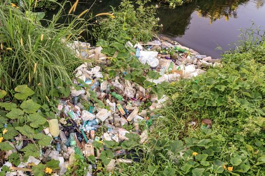 Plastic debris accumulated on a river edge with dirty water