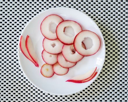 Slices of rose fruit in a plate on a white surface