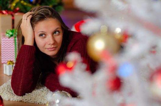 portrait of a beautiful brooding girl behind a Christmas tree