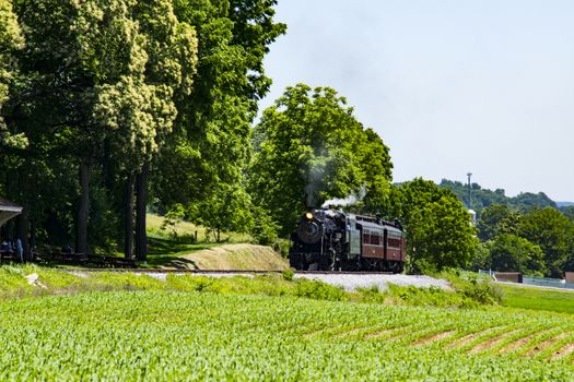 Steam Passenger Train Pulling into Picnic Area Blowing Smoke on a Sunny Summer Day