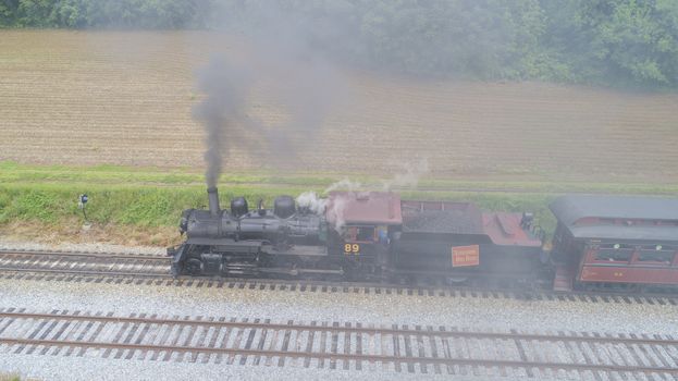 Ariel View of a Steam Passenger Train Pulling into Picnic Area Blowing Smoke on a Sunny Summer Day as seen by a Drone