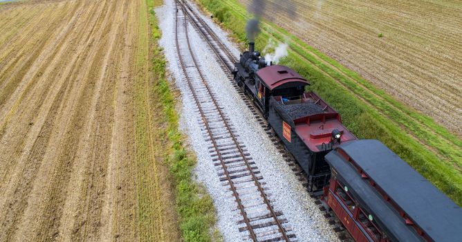 Ariel View of a Steam Passenger Train Pulling into Picnic Area Blowing Smoke on a Sunny Summer Day as seen by a Drone