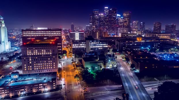 Cinematic aerial view of urban downtown Los Angeles city skyline and streets at night