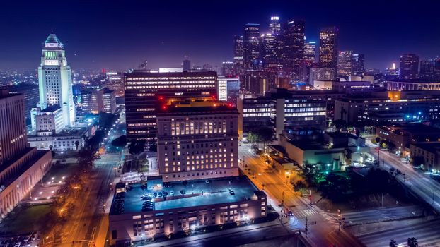 Cinematic aerial view of urban downtown Los Angeles city skyline and streets at night