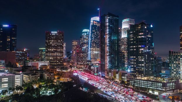 Cinematic aerial view of urban downtown Los Angeles city skyline and streets at night