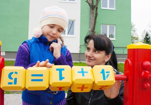 mom and daughter playing in the playground cubes with numbers