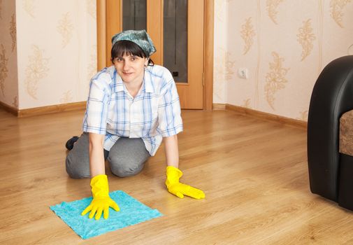 young woman cleaning the floor with a rag