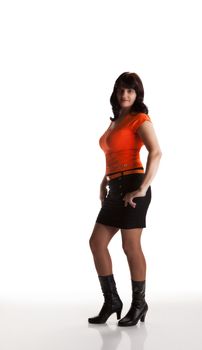 young beautiful woman in an orange shirt and black skirt posing standing in the studio on white background