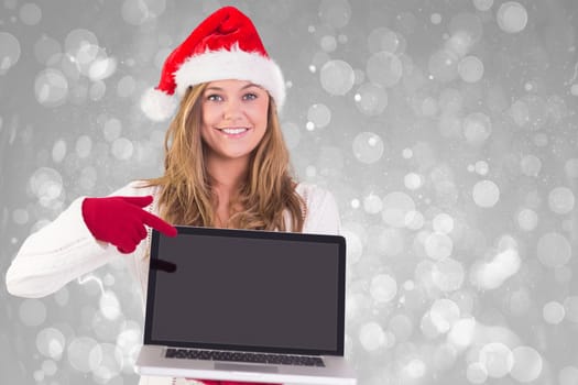 Festive blonde pointing to laptop against grey abstract light spot design