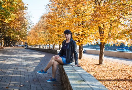 young brunette smiling woman on a walk in the park on sunny autumn day