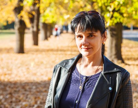 young brunette smiling woman on a walk in the park on sunny autumn day