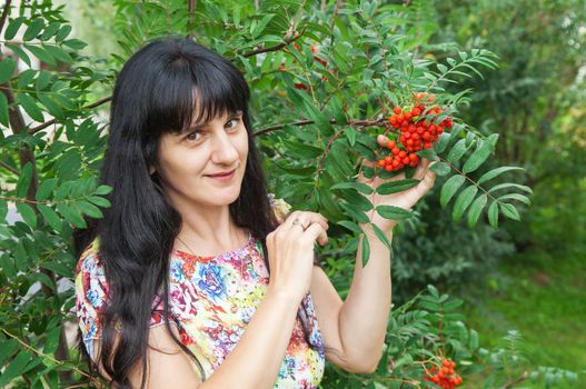 beautiful young smiling brunette near rowan tree