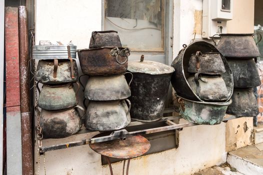 Several old cauldrons in heap in front of a facade