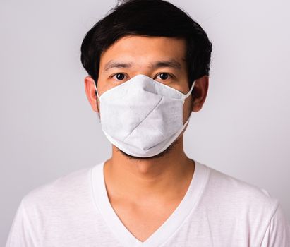 Closeup Asian handsome Man wearing surgical hygienic protective cloth face mask against coronavirus, studio shot isolated white background, COVID-19 medical concept