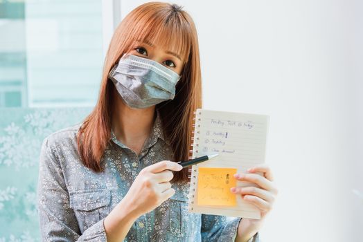 Work from home concept, Asian young business woman wearing face mask protective quarantines disease pandemic coronavirus or COVID-19 her video chat conference call and present report at home office