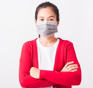 Asian adult woman stand crossed arm wearing red shirt and face mask protective against coronavirus or COVID-19 virus or filter dust pm2.5 and air pollution, studio shot isolated white background