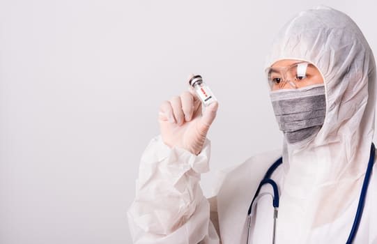 Asian female woman doctor or nurse in PPE uniform and gloves wearing face mask protective in laboratory holding medicine vial coronavirus vaccine bottle and on bottle has "COVID-19 VACCINE" text label