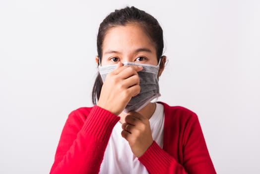 Closeup of portrait Asian adult woman wearing red shirt and face mask protective against coronavirus or COVID-19 virus showing demonstrating correct step, studio shot isolated white background