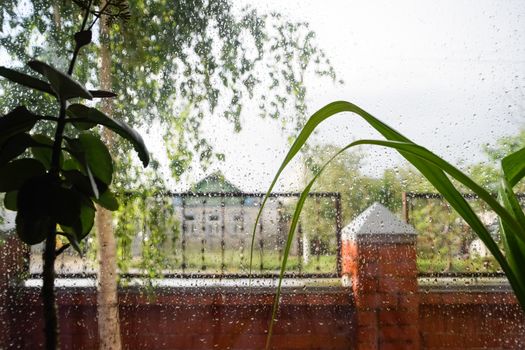 Raindrops on the window pane. Blurred background outside the window in the rain.