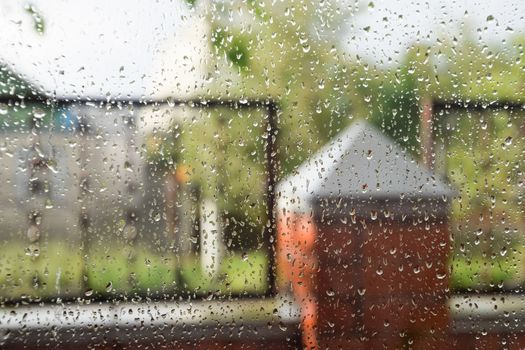 Raindrops on the window pane. Blurred background outside the window in the rain.