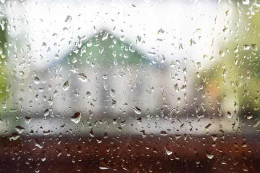 Raindrops on the window pane. Blurred background outside the window in the rain.