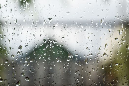 Raindrops on the window pane. Blurred background outside the window in the rain.