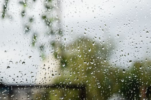 Raindrops on the window pane. Blurred background outside the window in the rain.