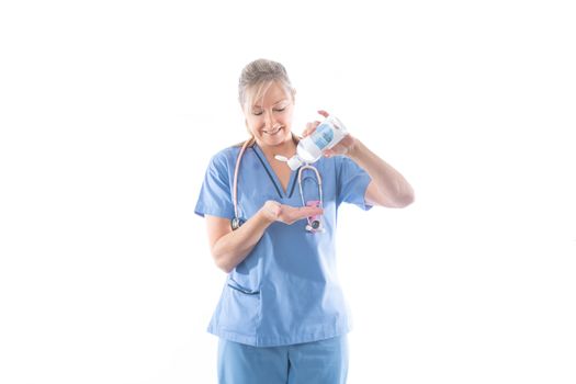 Happy nurse in blue scrubs showing or demonstrating the use of hand sanitize.   Hand hygiene has been increased during the coronavirus COVID-19 global pandemic