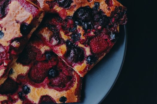 Berry pie on black plate, rustic homemade food with organic ingredients on black background