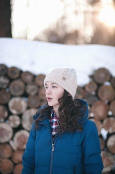 the beautiful young girl in a warm cap from wool of the alpaca in the winter forest. knitting