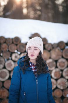 the beautiful young girl in a warm cap from wool of the alpaca in the winter forest. knitting