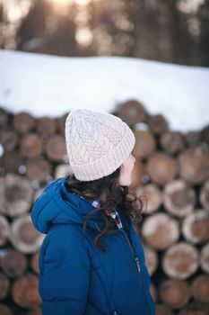 the beautiful young girl in a warm cap from wool of the alpaca in the winter forest. knitting