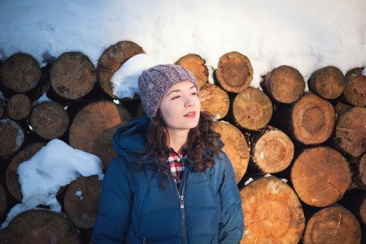 the beautiful young girl in a warm cap from wool of the alpaca in the winter forest. knitting