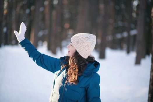 the beautiful young girl in a warm cap from wool of the alpaca in the winter forest. knitting