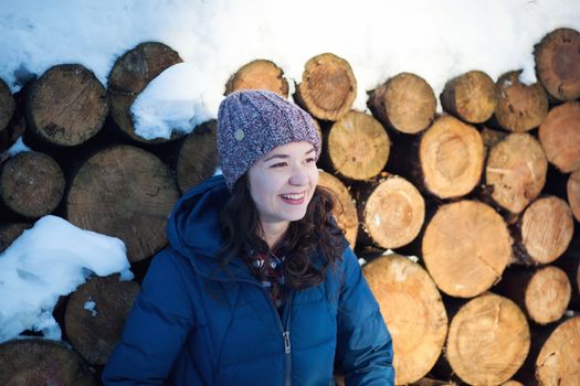 the beautiful young girl in a warm cap from wool of the alpaca in the winter forest. knitting