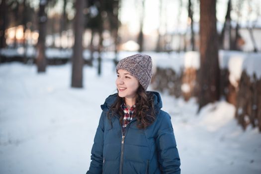 the beautiful young girl in a warm cap from wool of the alpaca in the winter forest. knitting