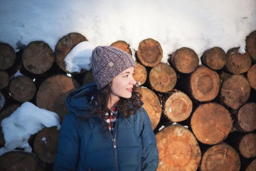 the beautiful young girl in a warm cap from wool of the alpaca in the winter forest. knitting